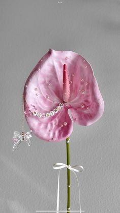 a pink flower with pearls on it in a vase