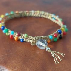 a close up of a bracelet on a wooden table with beads and tassels