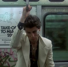 a man in a white jacket holding an umbrella over his head while standing next to a train