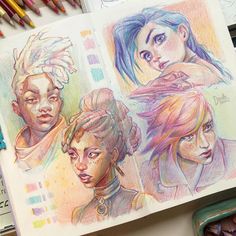 some colored pencils are laying on top of an open book with drawings in it