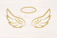 two golden angel wings with an halo above them on a white wooden background, in the shape of a circle