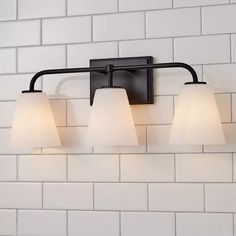 three light bathroom fixture with white glass shades on the top and bottom lights in an old - fashioned black finish