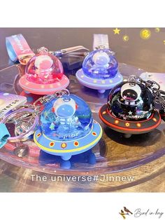 several keychains are sitting on top of a glass tray with space related items