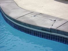 an empty swimming pool with blue water and tile around the edge is pictured in this image