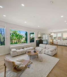 a large living room with white furniture and wood flooring on the hard wood floor