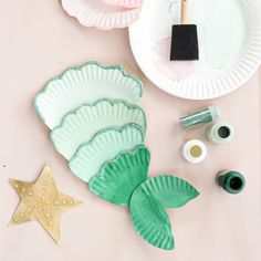 paper plates and craft supplies on a pink surface with starfish, seashells