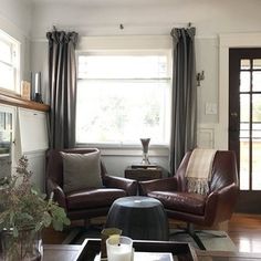 a living room filled with furniture and a fire place in front of a window on top of a hard wood floor