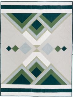 a green and white quilt with an abstract design on the front, along with two rows of squares