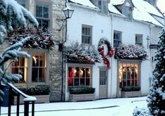 christmas decorations adorn the windows of an old building in snow - covered town square