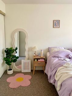 a bed room with a neatly made bed next to a mirror and a potted plant