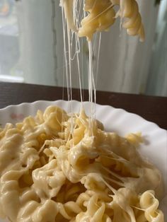 a plate with some noodles and cheese being drizzled on top of it