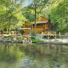 a house sitting on top of a lush green forest next to a river