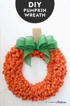 an orange and green yarn wreath hanging on a white wall with the words diy pumpkin wreath