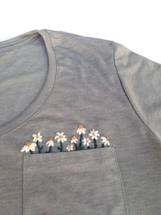 three daisies embroidered on the back of a gray t - shirt with white flowers