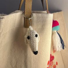 a crocheted sheep keychain hanging from a tote bag