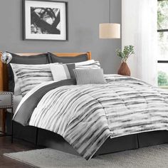 a bed with grey and white comforter in a bedroom