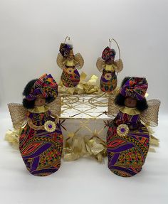 three african dolls sitting in front of a table with gold decorations on top of it