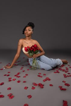 a woman sitting on the ground with roses around her