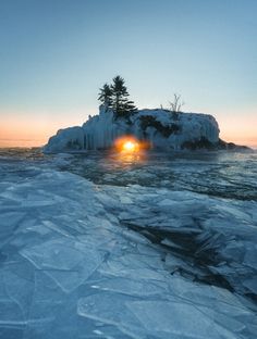 the sun is setting on an ice covered island