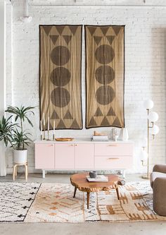 a living room with two large rugs and pink furniture in front of brick walls