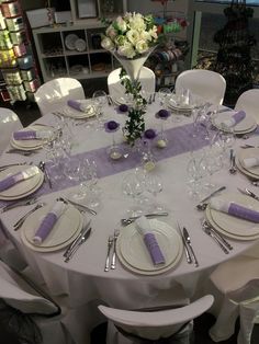 the table is set with white and purple place settings