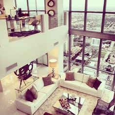 a living room filled with lots of furniture and large windows overlooking the cityscape