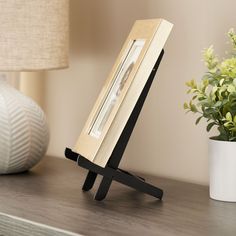 "Find this Black Mission Style Easel by Studio Décor® at Michaels. com. It's perfect for displaying straight-edged objects like frames, books, square plates and miniature whiteboards. Traditional-style easel looks great on a tabletop or countertop. It's perfect for displaying straight-edged objects like frames, books, square plates and miniature whiteboards. Details: Black Available in multiple sizes Wood | Black Mission Style Easel by Studio Decor® | 9\" x 4.75\" | Michaels®" Tabletop Photo Display Ideas, Photo Table Display, Picture Frame On Table, Table Picture Frame, Book Easel, Degree Display, Entrance Tables, Art Booth, Table Top Frame