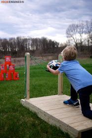 a young boy is playing with a soccer ball on a wooden platform in the grass