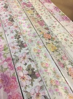 the table is covered with many different colored florals and flowers on white wood planks