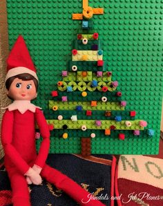 an elf is sitting next to a lego christmas tree