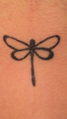 a dragonfly tattoo on the back of a woman's neck