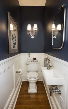 a white toilet sitting under two mirrors in a bathroom