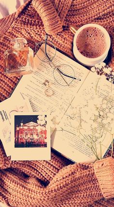 an open book on top of a bed next to a cup of coffee and glasses