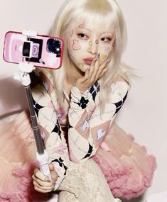 a woman with white hair and makeup holding a cell phone