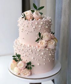 a three tiered cake with flowers and pearls on top is sitting on a table