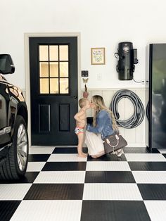 a woman kneeling down next to a child in front of a black and white checkered floor