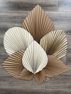 three folded paper fan shapes sitting on top of a wooden floor