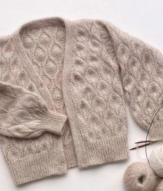 a pair of sweaters and yarn on a white surface