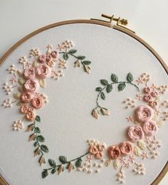 an embroidered letter o with pink flowers and green leaves