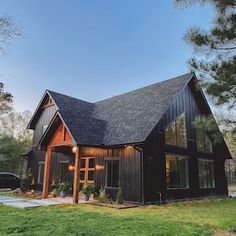 a large black house sitting on top of a lush green field