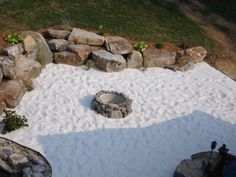 an aerial view of a fire pit surrounded by rocks and sand in the middle of a yard