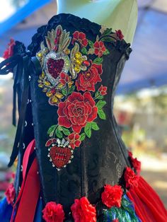 a black dress with red and blue flowers is on display at an outdoor market stall