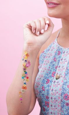 a woman with a flowered bracelet on her left arm and the wrist is covered in colorful beads