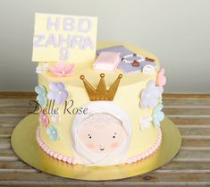 a yellow cake decorated with flowers and a princess's crown on top is sitting on a wooden table