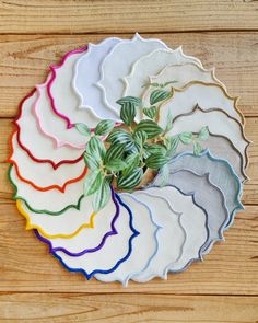 a bunch of paper plates that are sitting on a wooden table with a plant in the middle