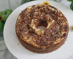 a cake sitting on top of a white plate covered in nuts and other toppings