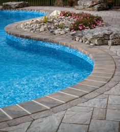 an empty swimming pool surrounded by rocks and flowers