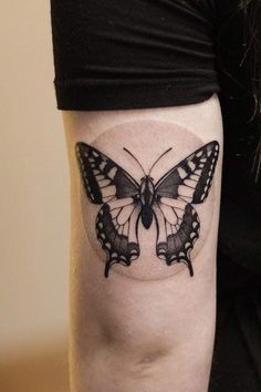 a black and white butterfly tattoo on the right arm, it looks like an insect