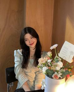 a woman sitting at a table with flowers in front of her