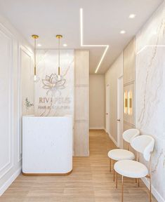 an empty hallway with white chairs and gold accents on the walls, along with a marble counter top